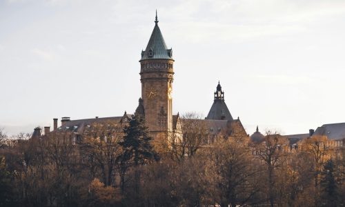 A scenic view of Luxembourg's gothic architecture surrounded by autumn trees, capturing its historic charm.