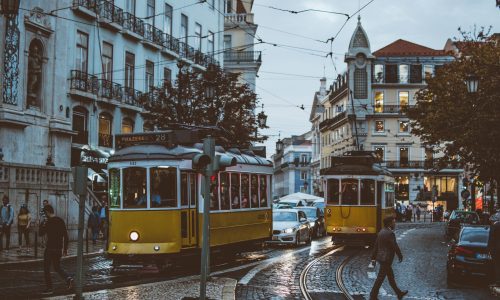 Scenic view of trams navigating the charming streets of Lisbon at dusk, capturing urban life and transportation.