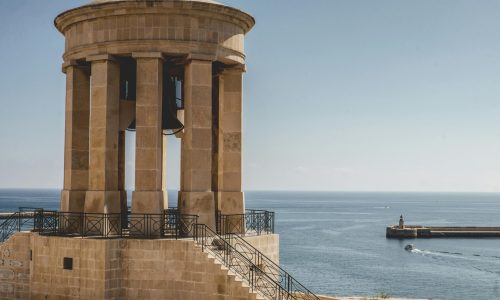 A scenic view of the historic bell tower in Valletta, Malta overlooking a tranquil seascape.