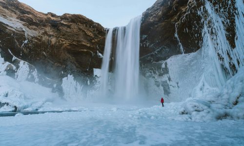 A breathtaking view of a towering waterfall amidst icy landscapes in Iceland.